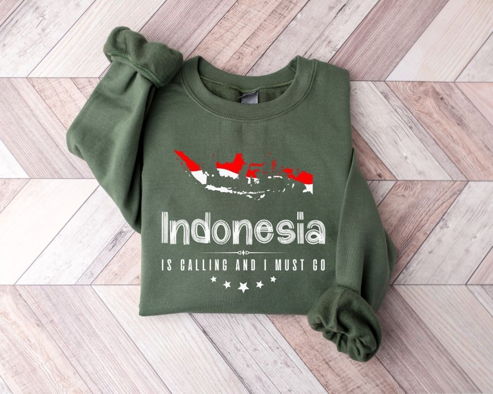Military green sweatshirt with 'Indonesia is calling and I must go' text on a wooden floor