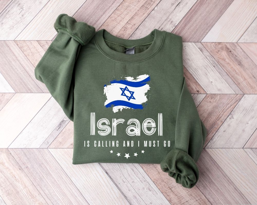 A millitray green sweatshirt featuring the Israel flag and text, placed on a wooden floor.
