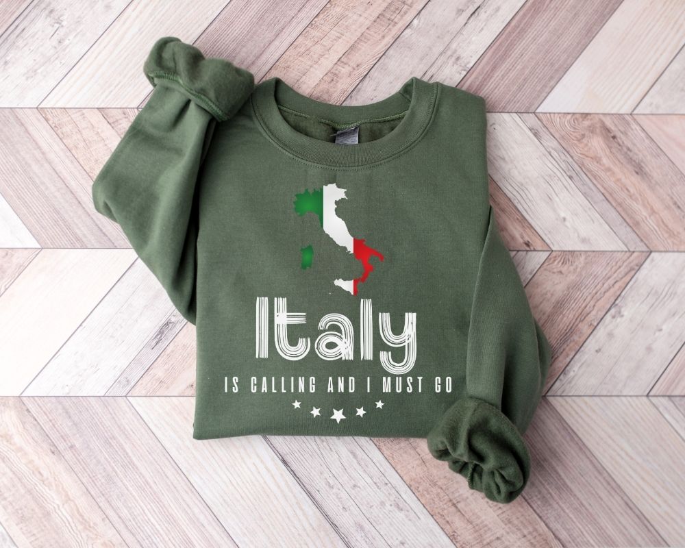 A millitray green sweatshirt featuring an Italian flag design and text, placed on a wooden floor.