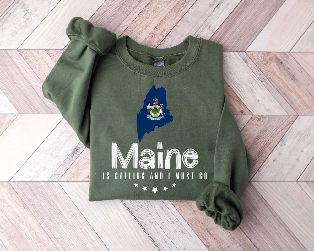 Military green sweatshirt with Maine design on a wooden floor