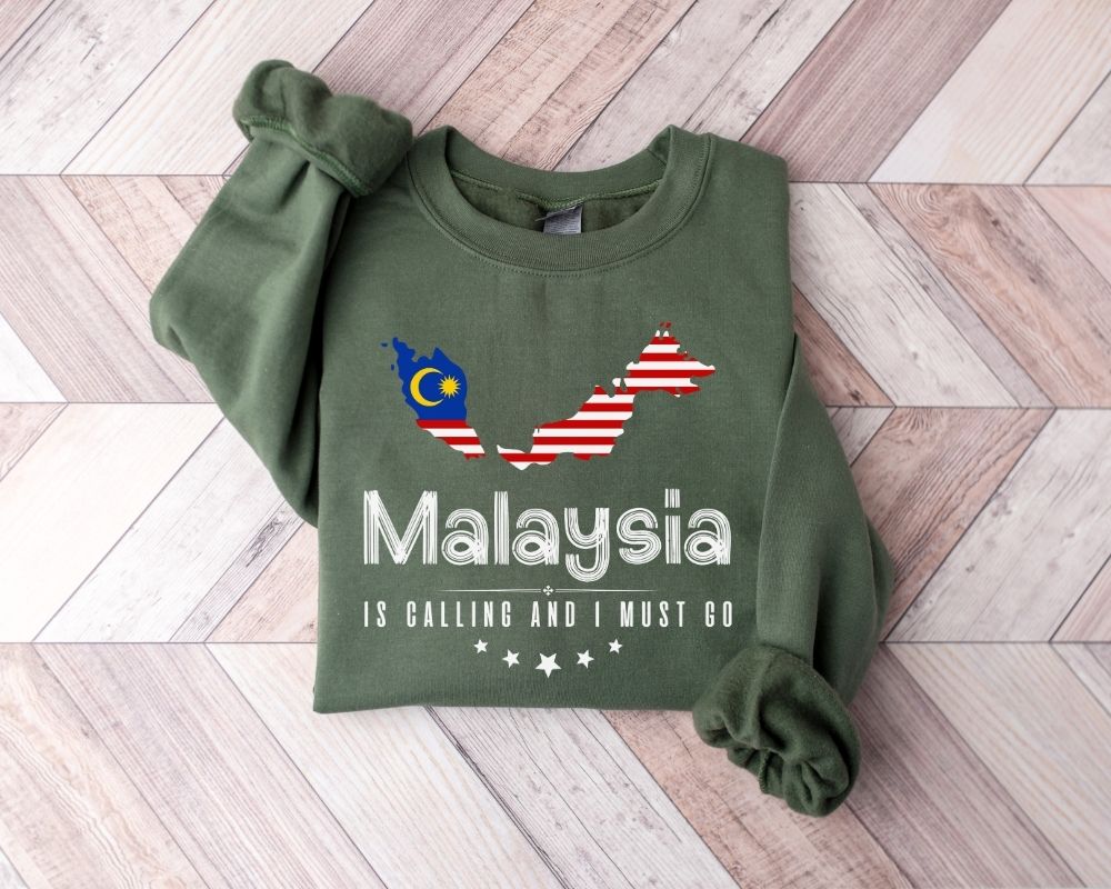 Military green sweatshirt with Malaysian and American flag design on a wooden floor