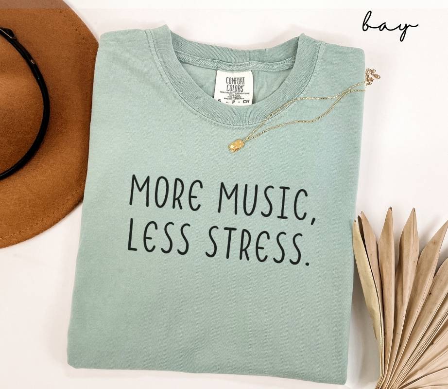Light green (bay) t-shirt with 'More Music, Less Stress' text on a white background