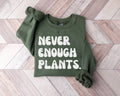 Military green sweatshirt with 'NEVER ENOUGH PLANTS' text on a wooden floor