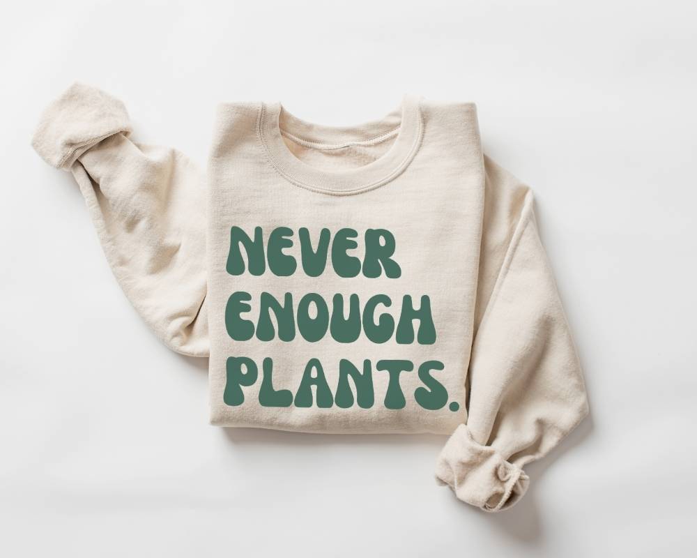 Beige (sand) sweatshirt with 'NEVER ENOUGH PLANTS' text on a white background