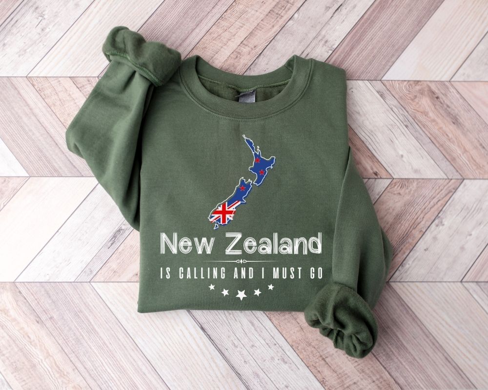 Military green sweatshirt with New Zealand design on a wooden floor
