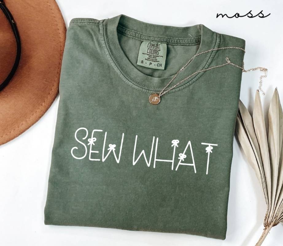 Folded green (moss) t-shirt with 'SEW WHAT' text on a white background