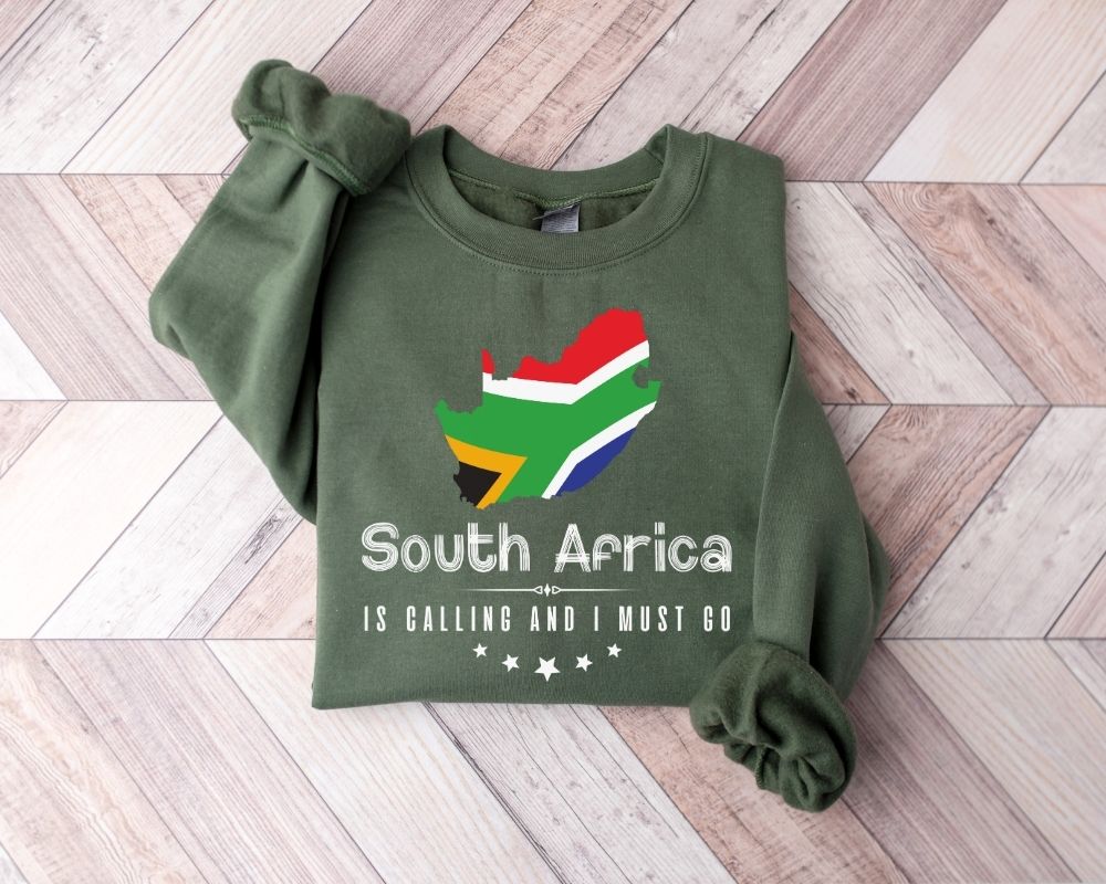 A military green sweatshirt featuring a design of the South African flag and text placed on a wooden floor.