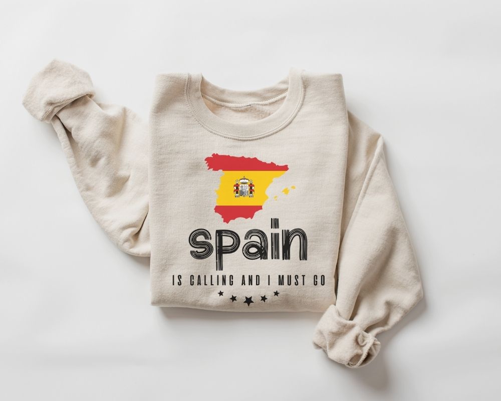 Beige (sand) sweatshirt featuring the Spanish flag along with text, displayed on a white background.