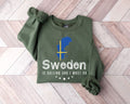 Military green sweatshirt with Swedish design and text on a wooden floor