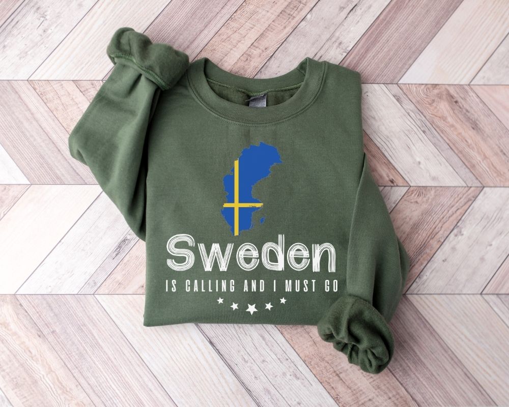 Military green sweatshirt with Swedish design and text on a wooden floor