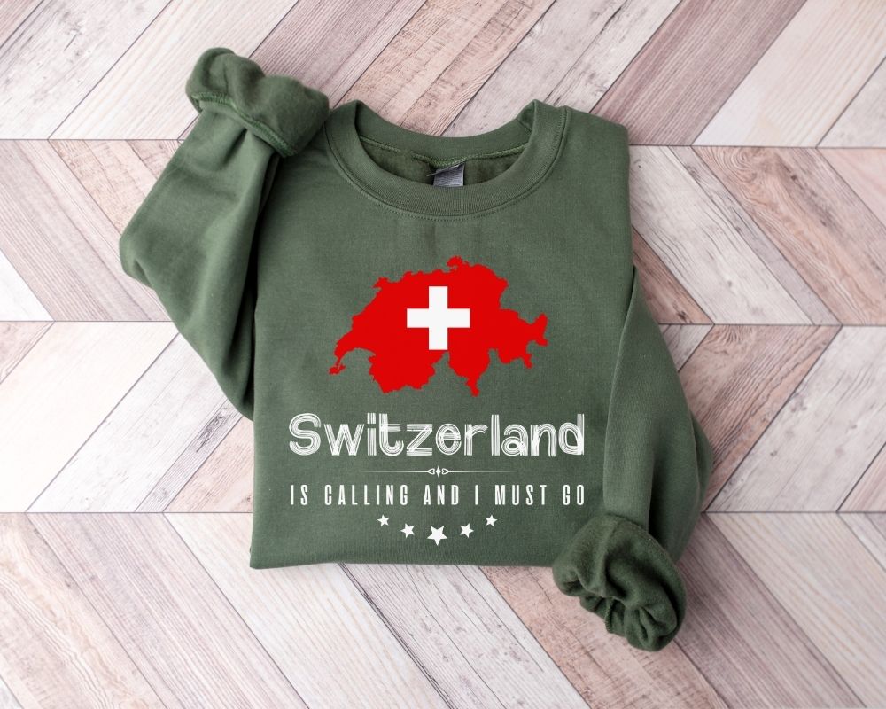 Military green sweatshirt with Swiss flag design on a wooden floor