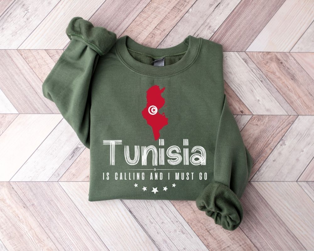 Military green sweatshirt with red and white graphics and text on a wooden floor