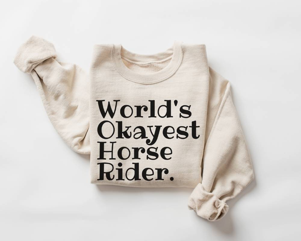 Beige (sand) sweatshirt with 'World's Okayest Horse Rider' text on a white background